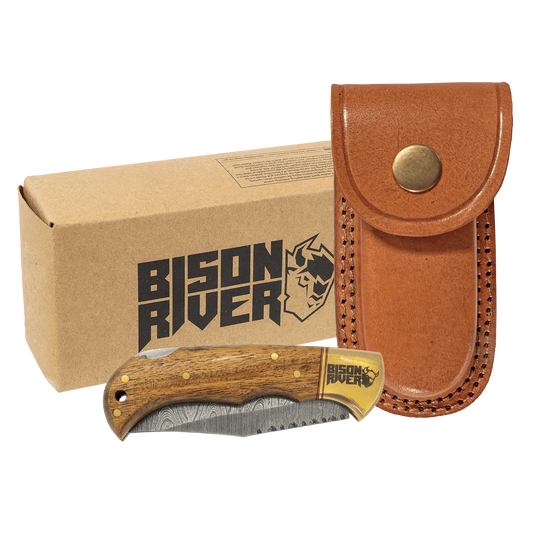 A Bison River knife with a Damascus blade and a brown leather sheath, displayed next to its packaging box.
