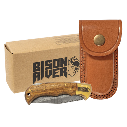 A Bison River knife with a Damascus blade and a brown leather sheath, displayed next to its packaging box.