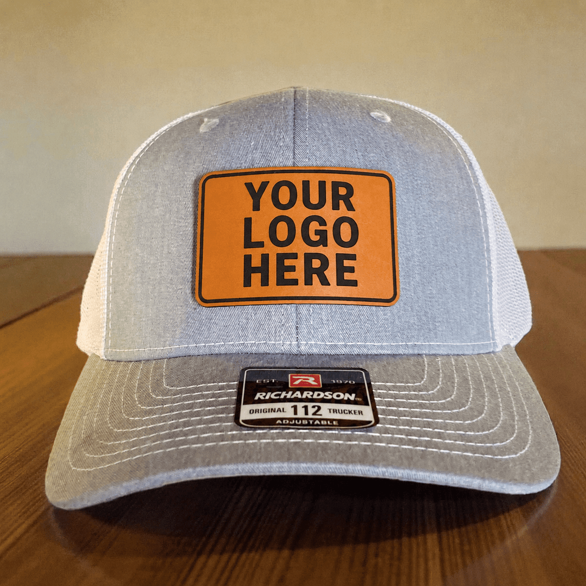 Gray and white Richardson 112 trucker hat with a tan Your Logo Here leatherette patch
