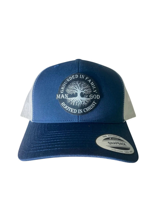 A blue leather patch trucker hat that says "Man of God - Grounded in Family, Rooted in Christ" on the patch with white mesh on the back half of the hat on a white background.