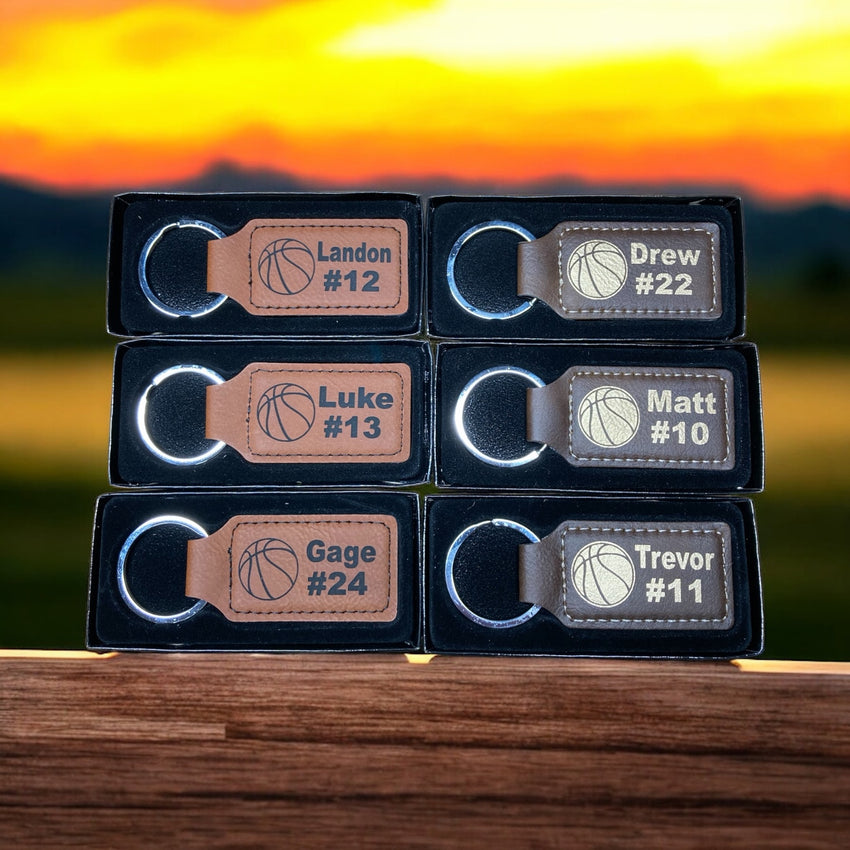 Six personalized leatherette basketball keychains engraved with individual names and numbers